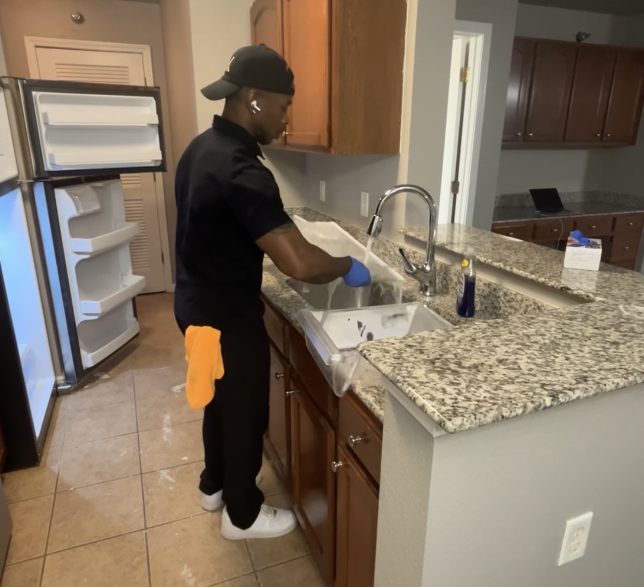 A Well Kept team member cleaning a kitchen sink and work area